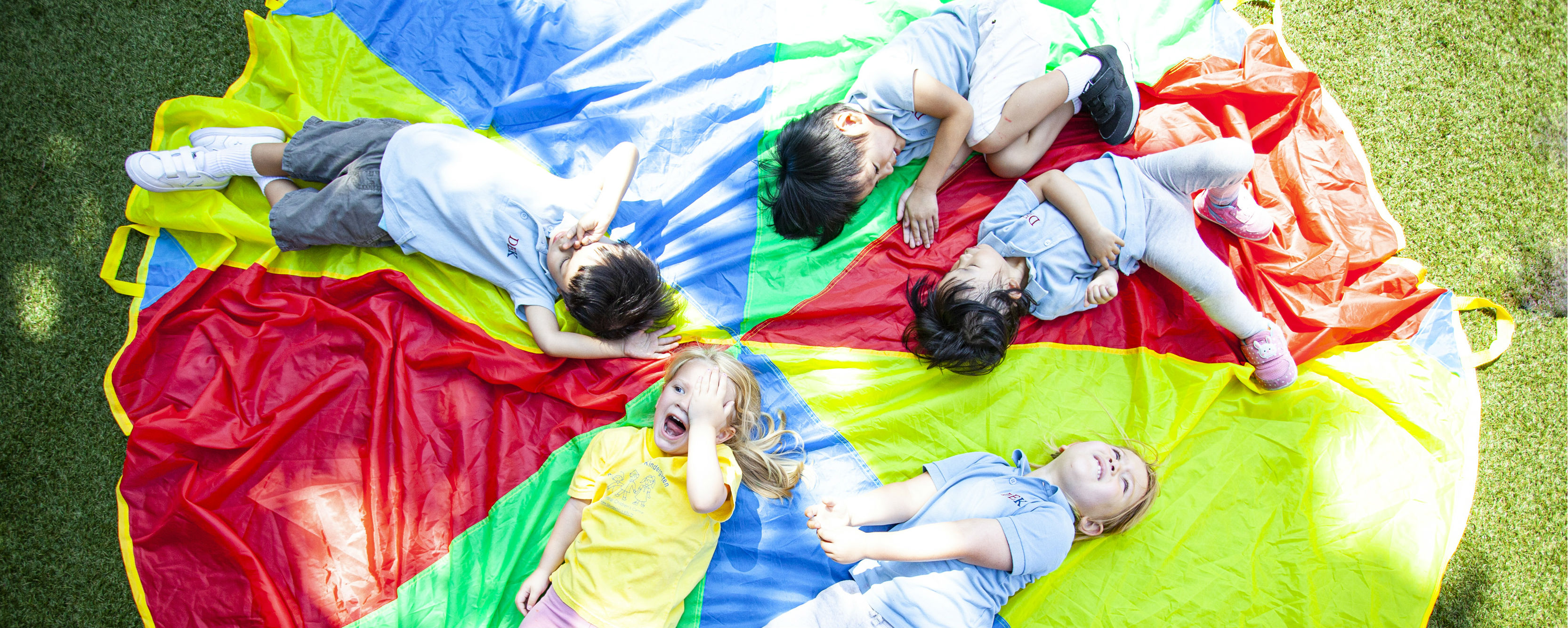 Vision Kindergarten children lying on colourful circle on grass